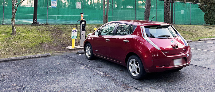 A burgandy Nissan Leaf is parked at an EV charging station in Bowen Park, Nanaimo